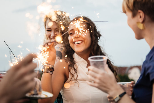 Young women having fun on a rooftop with sparklers.