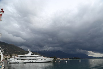 Luxury yacht at the pier of the marina in Porto Montenegro with cloudy dark sky