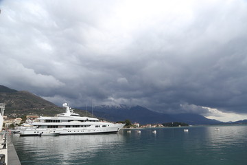 Fototapeta na wymiar Luxury yacht at the pier of the marina in Porto Montenegro with cloudy dark sky