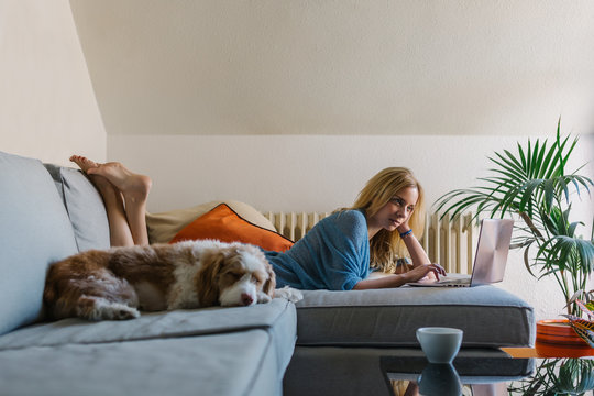 Beautiful Woman Using a Laptop while Her Dog is Sleeping