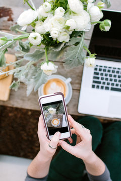 A woman taking a photo of her coffee with her smart phone