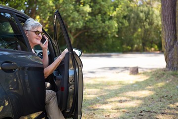 Senior woman talking on mobile phone in car