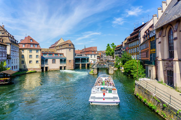 Traditional colorful houses in La Petite, with tourists taking a boat ride along traditional colorful houses on idyllic river Lauch in summer, Colmar, Alsace, France - obrazy, fototapety, plakaty