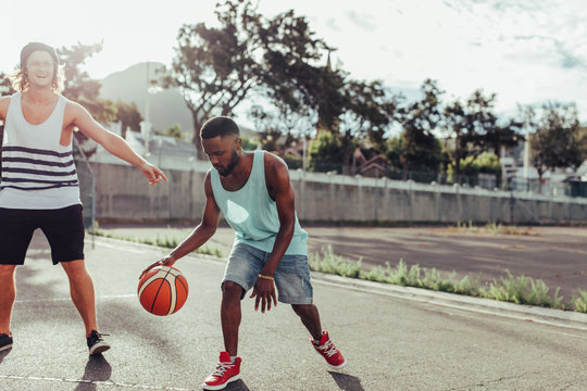 Two young men playing basketball