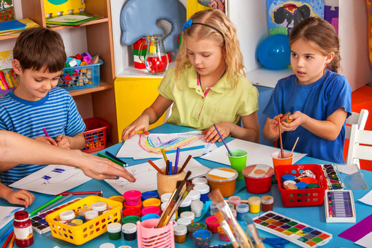 Small students painting in art school class. Children boy and girl drawing by paints on table. Portrait of kids in kindergarten. European children's home.