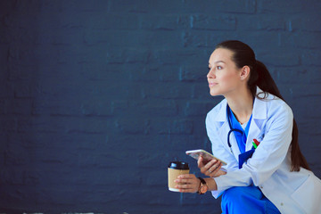 Young woman doctor sitting with your phone. Woman doctors.