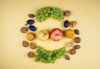 Autumn fruits and nuts on yellow background.
