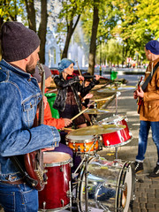 Festival music band in autumn park. Hands playing on percussion instruments in city park . Drums with sticks closeup of male musicians. People like street music.