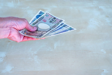 woman hand hold a Japanese currency yen bank note