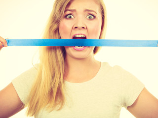 Attractive blonde woman biting tape on mouth.