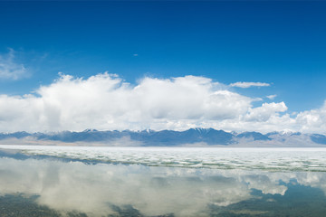 panoramic view of fluffy white clouds reflecting in mirror water of lake
