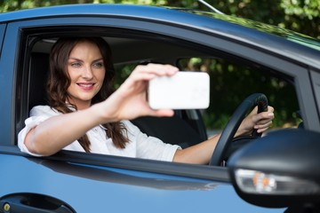 Obraz na płótnie Canvas Woman taking selfie with mobile phone in car