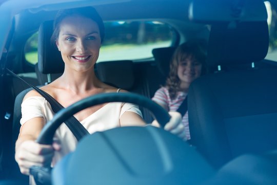 Woman driving a car while daughter sitting in the backseat of