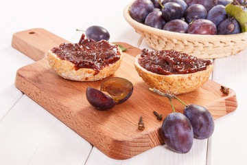 Fresh prepared sandwiches with plum jam on wooden cutting board, breakfast concept