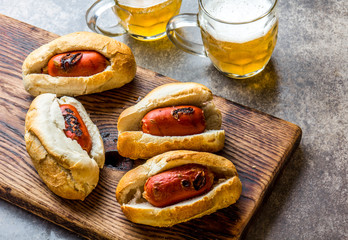 Choripan. Latin American Argentine and chilean food. Grilled chorizo sausages hot dogs served with beer, top view, stone background