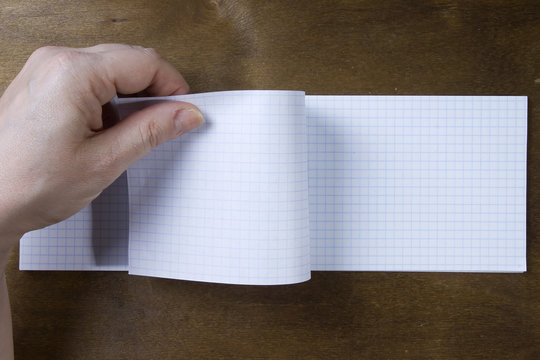 Hands turn pages of the notebook