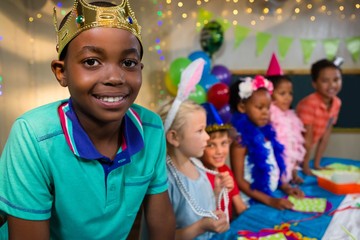 Portrait of boy wearing crown with friends in background