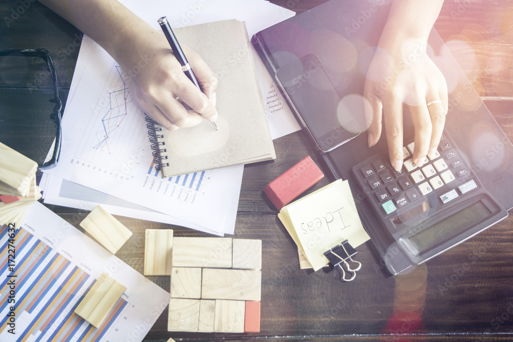 Poster business team using a calculator to calculate the numbers on his desk in a office.