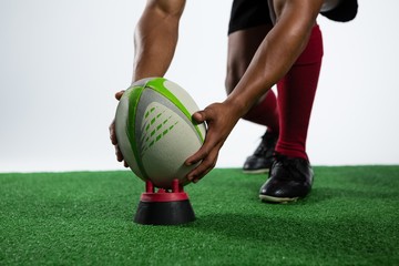 Low section of sportsman keeping rugby ball on tee