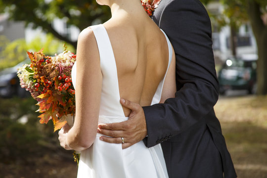 groom and bride with autumn bouquet outdoors. closeup of a married couple. Goose bumps and shivers at the bride. the bride in a wedding dress with a deep neckline at the back