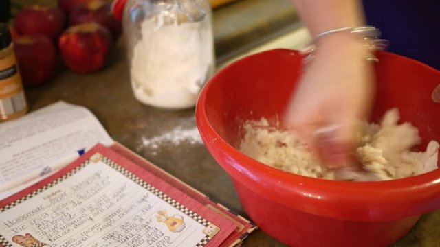 Woman mixing flour and milk in a red food bowl