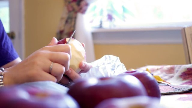 Woman Peeling the skin off an apple in the kitchen during Autumn months