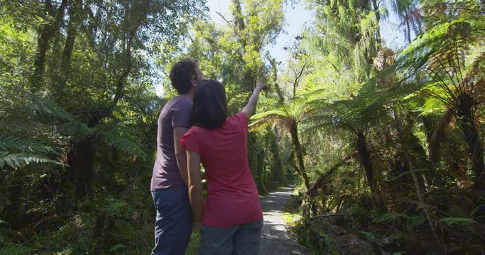 Hiking couple in New Zealand. People hiking in swamp forest nature landscape in Ship Creek on West Coast of New Zealand. Tourist couple pointing sightseeing tramping on South Island of New Zealand.