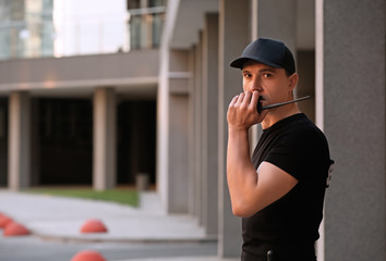 Male security guard with portable radio, outdoors