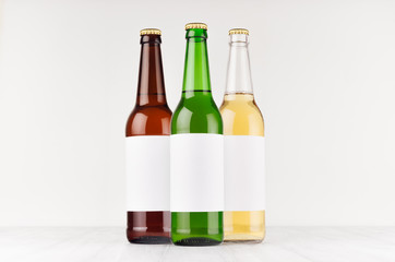 Beer bottles 500ml different colors with blank white label on white wooden board, mock up. Template for advertising, design, branding identity.