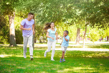 Naklejka na ściany i meble Young family with adopted African American boy having fun outdoors