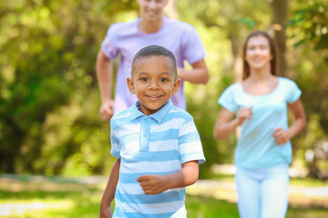 Young family with adopted African American boy having fun outdoors