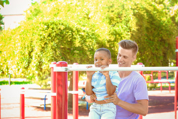 Young father with adopted African American boy on the sports ground