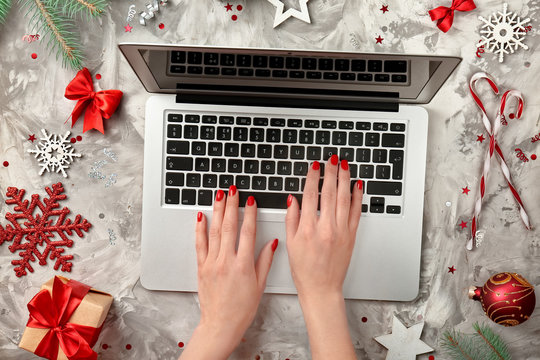 Hands of woman using laptop and Christmas decorations on light background