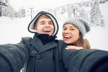 Fototapeta na wymiar Young and happy couple doing winter selfie outdoor. Christmas, New Year and people concept