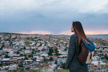 Young woman tourist from a high point looking at the sunset over the town and dreaming. Tourism,...
