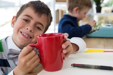Boy as business executive holding coffee mug in office
