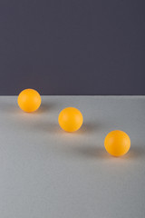 Abstract still life with three orange balls on a gray surface.