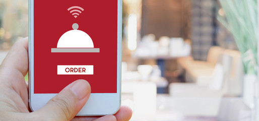 Hand holding smart phone with food online device on screen over blur restaurant background, banner wuth copy space, food online, food delivery concept