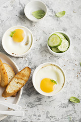 Breakfast for two. Eggs baked in the oven in ceramic portioned forms with toasted bread and slices of fresh cucumber. Top View.