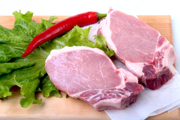 Raw pork chops with herbs and spices on cutting board. Ready for cooking.