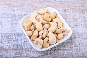 nuts cashews in white bowl on wooden background. Selective focus.