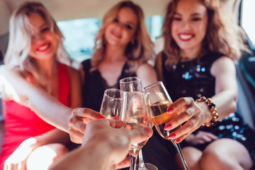 Pretty women having party in a limousine car and drinking champagne.