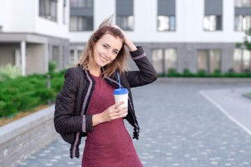 Cheerful woman in the street drinking morning coffee