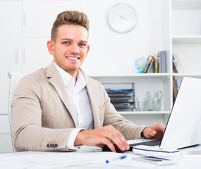 Smiling manager at office desk with laptop.