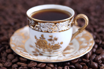 Morning cup of fragrant coffee standing on grains closeup