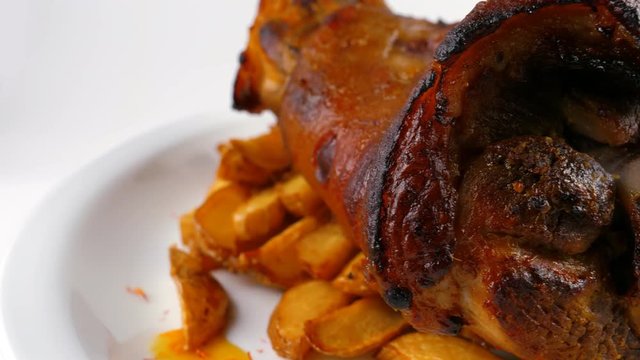 Roasted pork knuckle with potatoes and vegetables, served in Restaurant or Pub, close-up view, loop, 4K, ProRes codec, 422 HQ, ISO 100