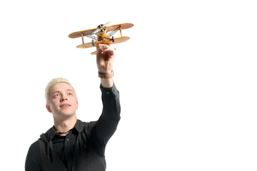 Fototapeta na wymiar Beautiful blond man dressed in black playing with a model airplane. Isolated