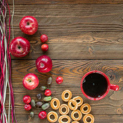 red cup of black tea and ripe red apples, actinidia berries, bagels on wooden table with decorative colorful  dry straw. top view - 172317027
