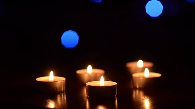 candles on the table in the dark, festive decoration of the room, against the background of colorful bokeh shining in the background