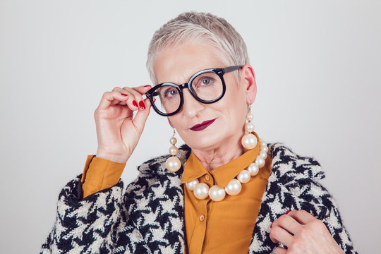 Stylish and elegant old woman in glasses on a white background.